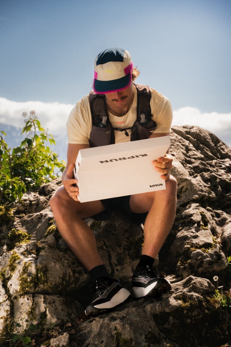 Homme assis sur des rochers avec boîte à pizza, exploration en nature.
